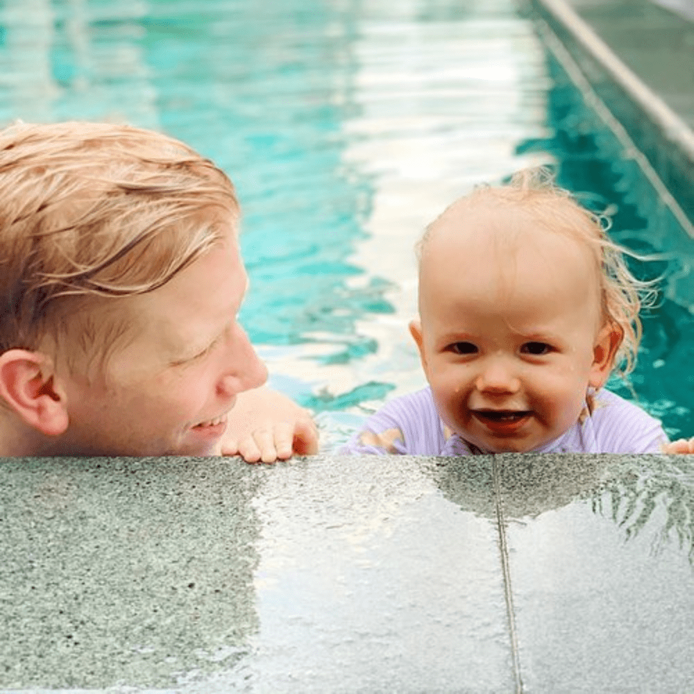 kidtastic dad and toddler hanging on pool ledge
